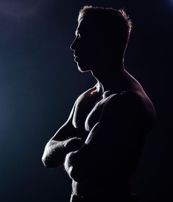 Man performing a controlled strength exercise in a dark studio with lilac light.